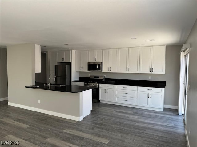 621 Carlos Julio Ave, North Las Vegas, NV 89031 - kitchen featuring appliances with stainless steel finishes, white cabinets, dark countertops, and dark wood-style flooring