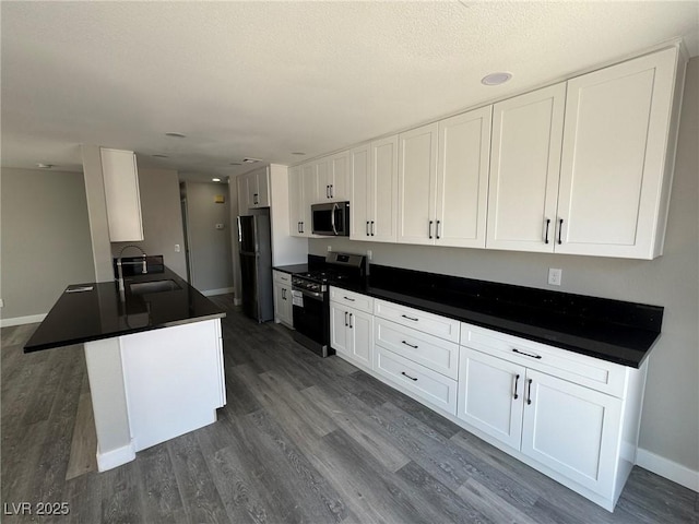 621 Carlos Julio Ave, North Las Vegas, NV 89031 - kitchen featuring stainless steel appliances, dark countertops, white cabinets, dark wood-style flooring, and a textured ceiling