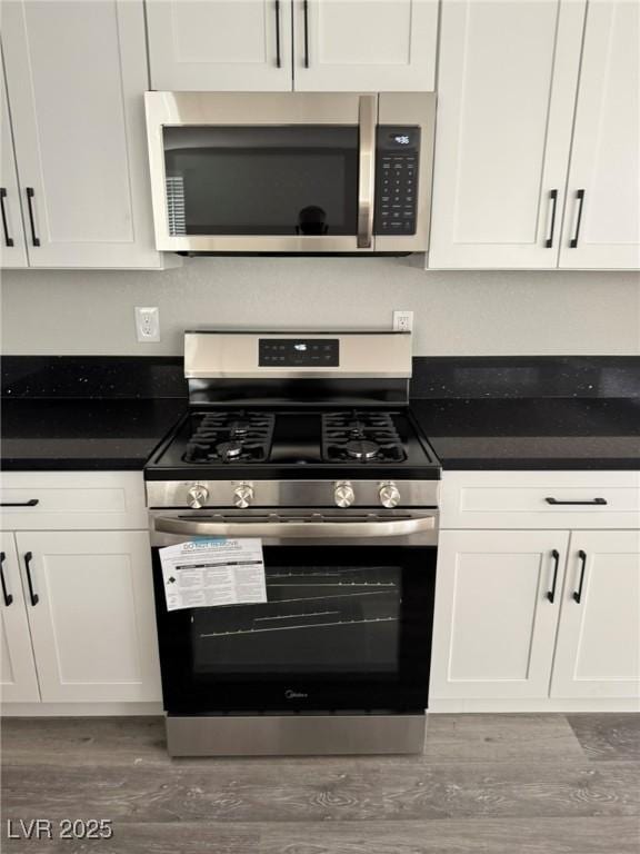 621 Carlos Julio Ave, North Las Vegas, NV 89031 - kitchen featuring stainless steel appliances, wood finished floors, white cabinets, and dark countertops
