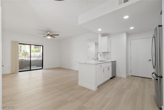 8250 N Grand Canyon Dr Unit 1050, Las Vegas, NV 89166 - kitchen with appliances with stainless steel finishes, a peninsula, ceiling fan, white cabinetry, and light wood-type flooring