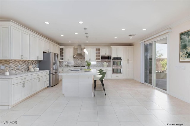 7112 Rancho De Taos Ct, Las Vegas, NV 89130 - kitchen featuring wall chimney range hood, appliances with stainless steel finishes, tasteful backsplash, ornamental molding, and a center island with sink
