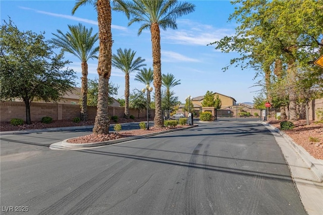7112 Rancho De Taos Ct, Las Vegas, NV 89130 - view of asphalt road featuring a gate, traffic signs, curbs, and a gated entry