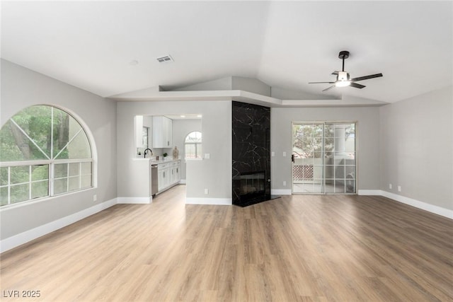 3408 Winterhaven St Unit 203, Las Vegas, NV 89108 - unfurnished living room featuring vaulted ceiling, a ceiling fan, light wood finished floors, healthy amount of natural light, and a premium fireplace