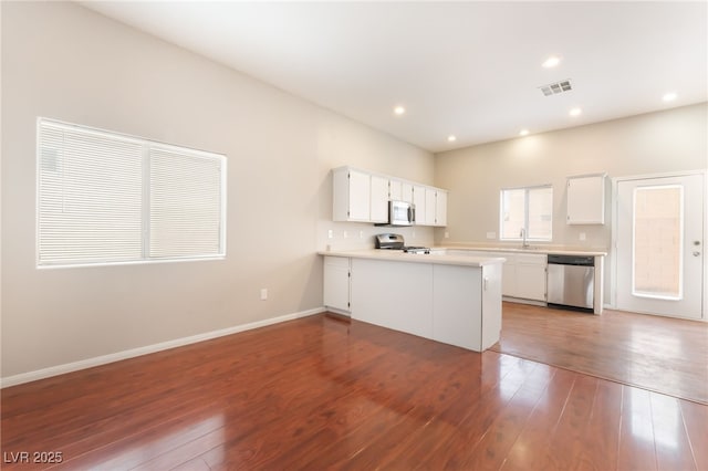 1635 Otto Merida Ave, Las Vegas, NV 89106 - kitchen with stainless steel appliances, a peninsula, white cabinetry, light countertops, and dark wood-style floors