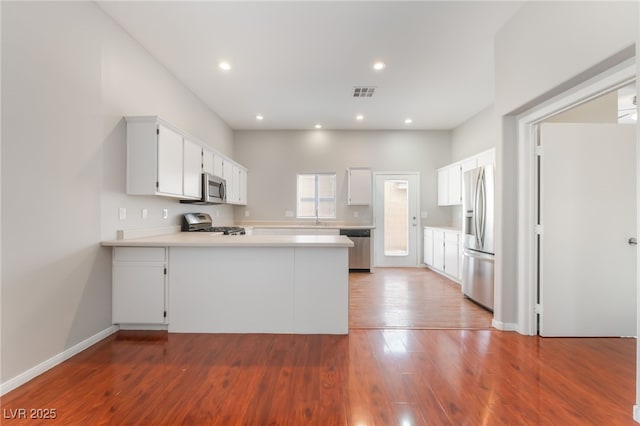 1635 Otto Merida Ave, Las Vegas, NV 89106 - kitchen with stainless steel appliances, a peninsula, wood finished floors, light countertops, and white cabinets