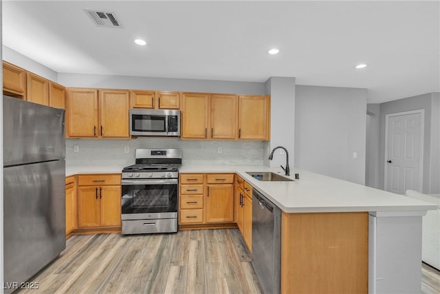 9074 Maycott Ave, Las Vegas, NV 89148 - kitchen featuring stainless steel appliances, a peninsula, light countertops, light wood finished floors, and tasteful backsplash