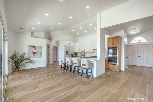 1144 Calico Ridge Dr, Henderson, NV 89011 - kitchen featuring stainless steel double oven, a kitchen bar, light countertops, light wood-style flooring, and recessed lighting