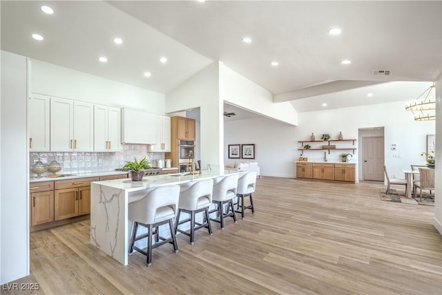 1144 Calico Ridge Dr, Henderson, NV 89011 - kitchen featuring a breakfast bar, light wood-style floors, tasteful backsplash, light stone countertops, and recessed lighting