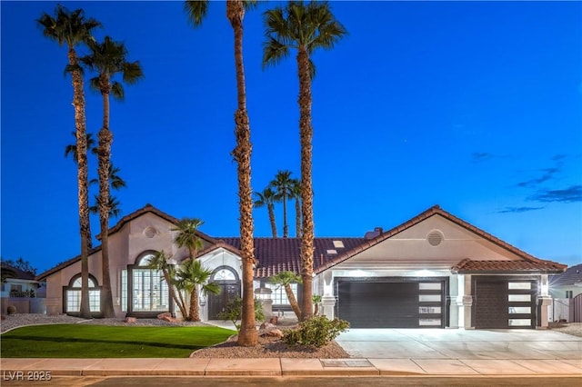 1144 Calico Ridge Dr, Henderson, NV 89011 - view of front of property with a garage, a tiled roof, concrete driveway, stucco siding, and a front lawn