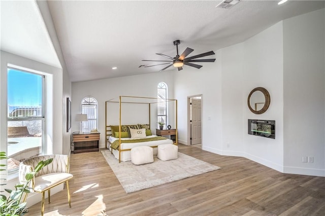 1144 Calico Ridge Dr, Henderson, NV 89011 - bedroom featuring multiple windows, a glass covered fireplace, wood finished floors, high vaulted ceiling, and recessed lighting