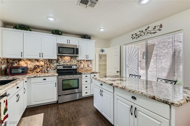 7068 Bright Springs Ct, Las Vegas, NV 89113 - kitchen featuring stainless steel appliances, dark wood-style floors, tasteful backsplash, white cabinetry, and healthy amount of natural light