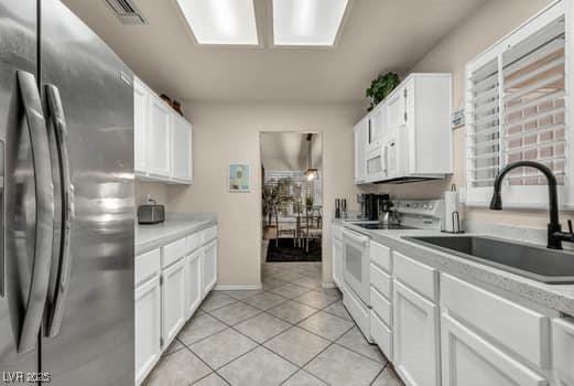 2135 Hallston St, Las Vegas, NV 89134 - kitchen with white appliances, white cabinets, light tile patterned floors, and light countertops