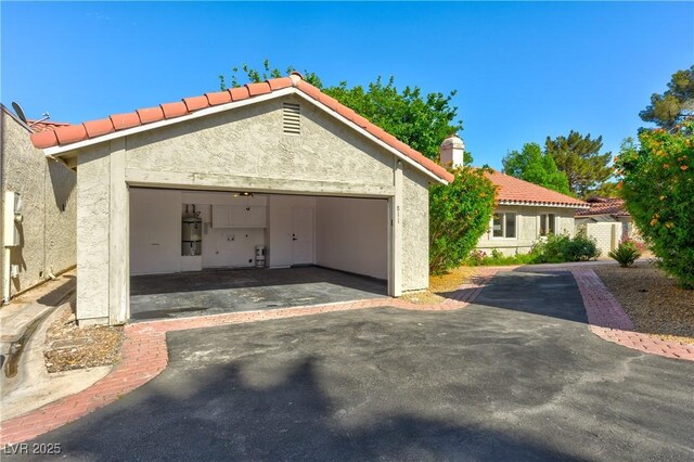 811 Spyglass Ln, Las Vegas, NV 89107 - view of front of property with stucco siding, a garage, a tiled roof, and a chimney