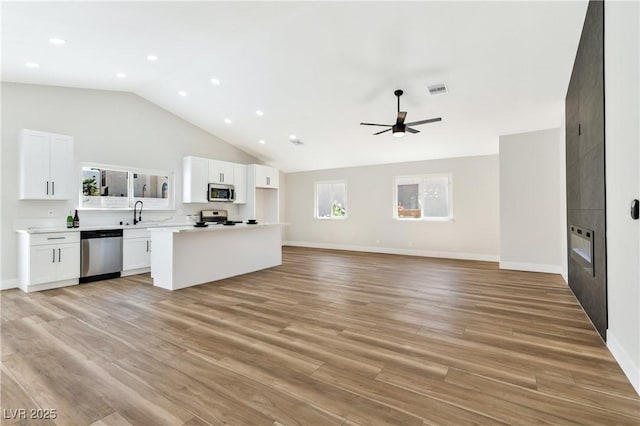 811 Spyglass Ln, Las Vegas, NV 89107 - kitchen with appliances with stainless steel finishes, open floor plan, white cabinets, a kitchen island, and light wood finished floors