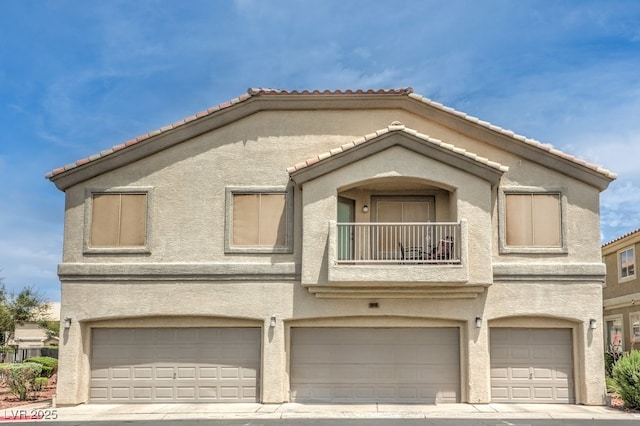 6068 Shyley St Unit 102, Henderson, NV 89011 - view of front of home featuring a balcony, an attached garage, stucco siding, and a tiled roof