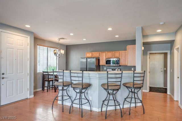 6068 Shyley St Unit 102, Henderson, NV 89011 - kitchen featuring stainless steel appliances, a kitchen breakfast bar, recessed lighting, a chandelier, and light wood-type flooring