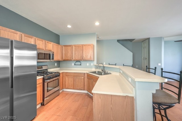 6068 Shyley St Unit 102, Henderson, NV 89011 - kitchen featuring appliances with stainless steel finishes, a peninsula, a kitchen breakfast bar, light wood finished floors, and recessed lighting
