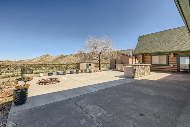 7790 Scottie St, Las Vegas, NV 89166 - view of patio / terrace featuring a mountain view, exterior kitchen, a fire pit, and a storage unit