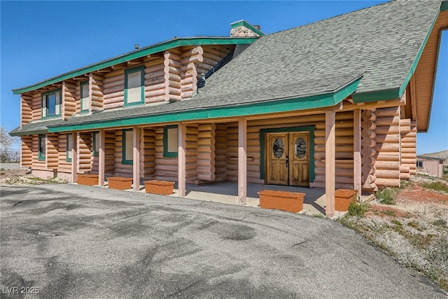 7790 Scottie St, Las Vegas, NV 89166 - log cabin featuring log exterior, a chimney, a shingled roof, and covered porch