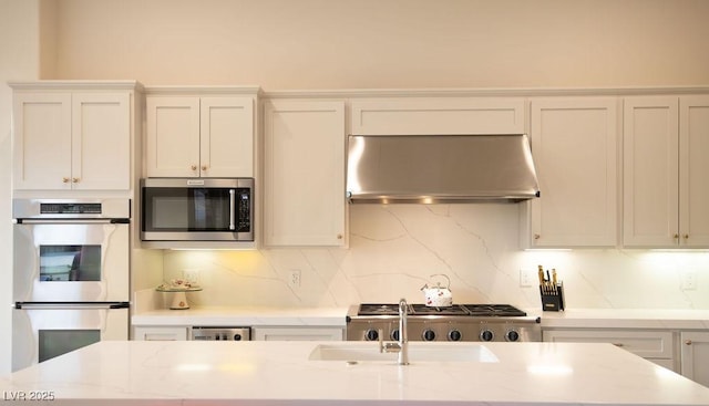 9 Knob Oak Dr, Henderson, NV 89052 - kitchen with stainless steel appliances, extractor fan, tasteful backsplash, white cabinetry, and light stone countertops