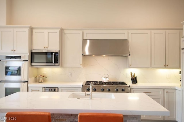 9 Knob Oak Dr, Henderson, NV 89052 - kitchen featuring extractor fan, appliances with stainless steel finishes, white cabinetry, tasteful backsplash, and light stone counters