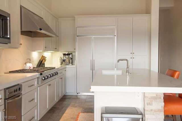 9 Knob Oak Dr, Henderson, NV 89052 - kitchen with stainless steel appliances, under cabinet range hood, white cabinets, an island with sink, and tasteful backsplash