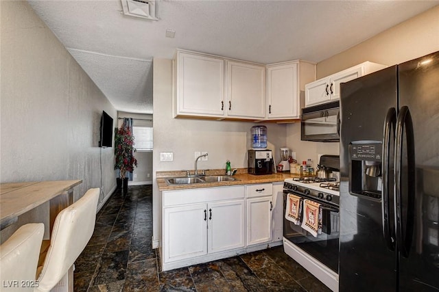3912 Palos Verdes St, Las Vegas, NV 89119 - kitchen featuring black appliances, dark stone finish flooring, a textured ceiling, and white cabinets