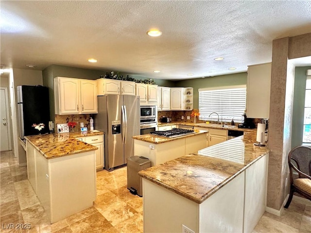 2975 Montessouri St, Las Vegas, NV 89117 - kitchen with stainless steel appliances, a peninsula, plenty of natural light, light stone countertops, and recessed lighting