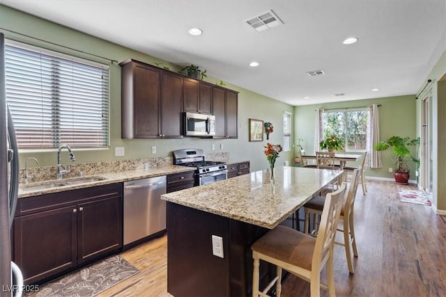 9305 Briar Bridge Ave, Las Vegas, NV 89148 - kitchen featuring appliances with stainless steel finishes, a breakfast bar area, a center island, light stone counters, and dark brown cabinets