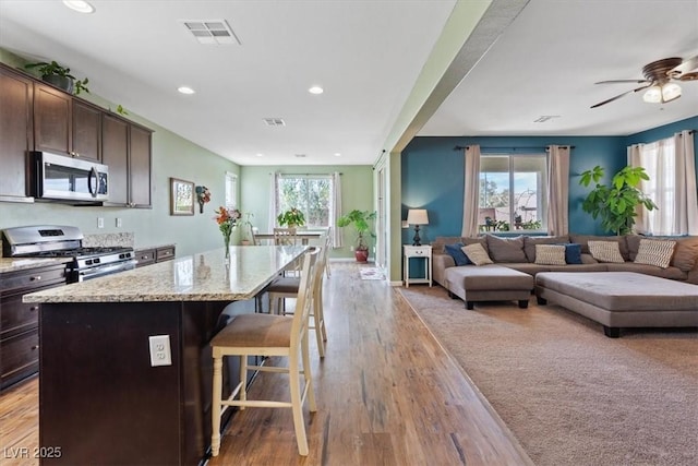 9305 Briar Bridge Ave, Las Vegas, NV 89148 - kitchen with stainless steel appliances, a breakfast bar, dark brown cabinetry, open floor plan, and recessed lighting
