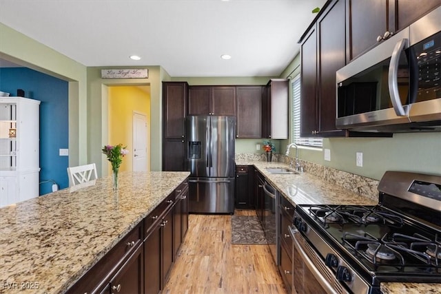 9305 Briar Bridge Ave, Las Vegas, NV 89148 - kitchen featuring stainless steel appliances, light wood-style floors, light stone counters, dark brown cabinets, and recessed lighting