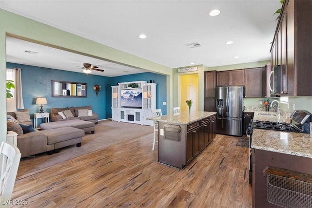 9305 Briar Bridge Ave, Las Vegas, NV 89148 - kitchen featuring appliances with stainless steel finishes, dark brown cabinetry, a kitchen island, light wood finished floors, and open floor plan