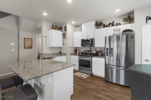 7515 Emerald Stars St Unit 102, North Las Vegas, NV 89084 - kitchen featuring stainless steel appliances, a peninsula, a breakfast bar area, white cabinetry, and light stone counters