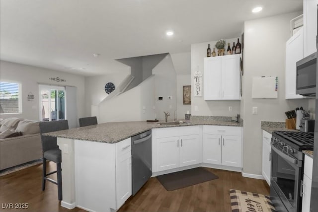 7515 Emerald Stars St Unit 102, North Las Vegas, NV 89084 - kitchen with appliances with stainless steel finishes, open floor plan, a peninsula, dark wood-style flooring, and white cabinetry