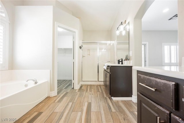 3882 Genoa Dr, Las Vegas, NV 89141 - bathroom with a stall shower, vanity, wood finished floors, a bath, and a walk in closet