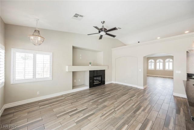 3882 Genoa Dr, Las Vegas, NV 89141 - unfurnished living room featuring a ceiling fan, wood finished floors, a tile fireplace, a chandelier, and lofted ceiling
