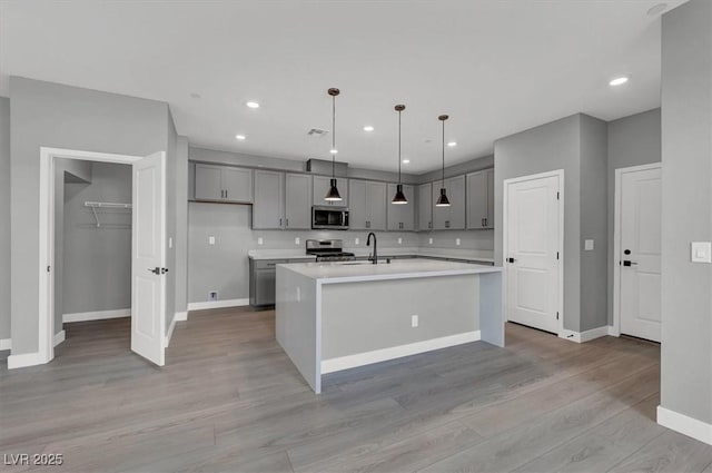 514 Fairview Hills St, Las Vegas, NV 89138 - kitchen featuring appliances with stainless steel finishes, gray cabinetry, light countertops, light wood-style flooring, and a center island with sink