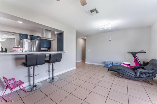 2690 Diamante Cir, Las Vegas, NV 89121 - kitchen with freestanding refrigerator, blue cabinetry, light countertops, a kitchen breakfast bar, and light tile patterned flooring