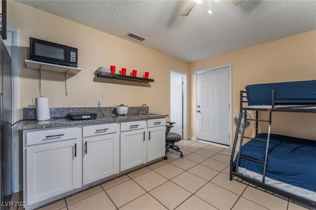 2690 Diamante Cir, Las Vegas, NV 89121 - kitchen with black microwave, white cabinets, a textured ceiling, light tile patterned floors, and a ceiling fan