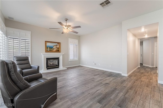 8424 Willowleaf Ct, Las Vegas, NV 89128 - unfurnished living room featuring a ceiling fan, wood finished floors, and a glass covered fireplace