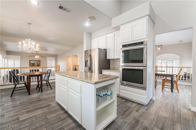 8424 Willowleaf Ct, Las Vegas, NV 89128 - kitchen with appliances with stainless steel finishes, a chandelier, wood finished floors, a center island, and white cabinets