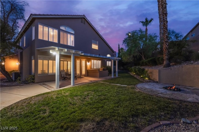 8424 Willowleaf Ct, Las Vegas, NV 89128 - back of property at dusk with a fire pit, a patio area, stucco siding, and a yard