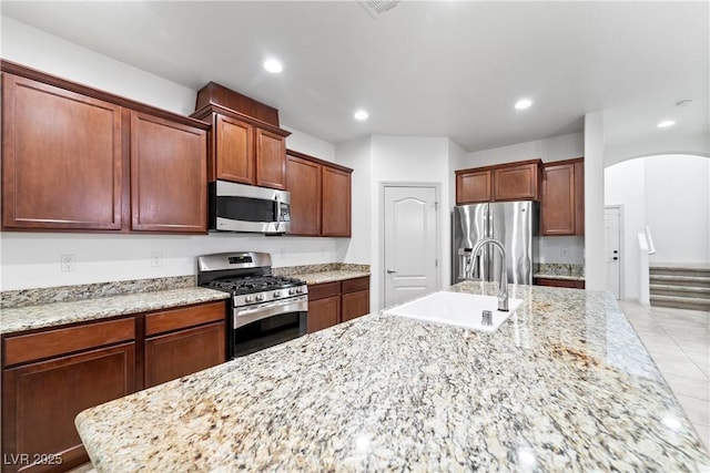9217 Apollo Heights Ave, Las Vegas, NV 89149 - kitchen with stainless steel appliances, arched walkways, a large island, recessed lighting, and light stone counters