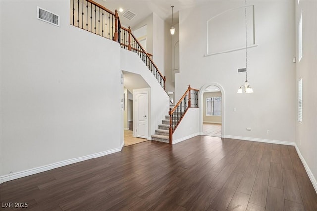 5541 Meridian Rain St, North Las Vegas, NV 89031 - unfurnished living room with a towering ceiling, wood finished floors, stairs, a chandelier, and arched walkways