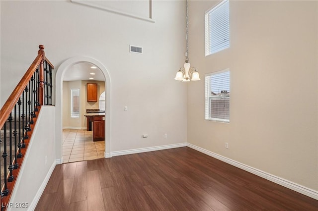 5541 Meridian Rain St, North Las Vegas, NV 89031 - spare room featuring dark wood-type flooring, a chandelier, arched walkways, a towering ceiling, and stairway