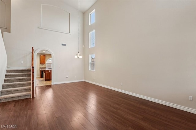 5541 Meridian Rain St, North Las Vegas, NV 89031 - unfurnished living room with arched walkways, dark wood finished floors, stairs, and a high ceiling