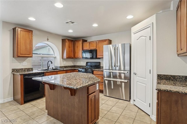 5541 Meridian Rain St, North Las Vegas, NV 89031 - kitchen with black appliances, dark stone counters, a center island, light tile patterned flooring, and recessed lighting