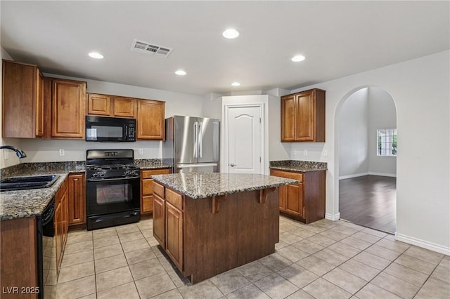 5541 Meridian Rain St, North Las Vegas, NV 89031 - kitchen featuring black appliances, arched walkways, dark stone countertops, a kitchen island, and recessed lighting