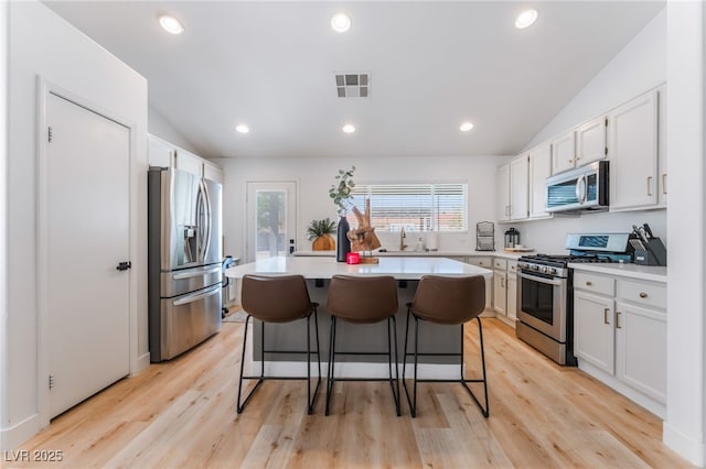 7909 Lovely Pine Pl, Las Vegas, NV 89143 - kitchen featuring stainless steel appliances, vaulted ceiling, light countertops, a breakfast bar, and a center island