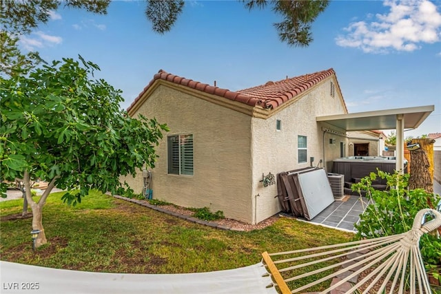 3938 Redfield Ave, North Las Vegas, NV 89032 - view of property exterior featuring a hot tub, stucco siding, a tiled roof, a patio area, and a lawn